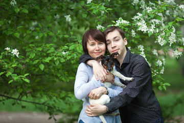 Portrait of happy mather with son and dog Jack Russell in summer park