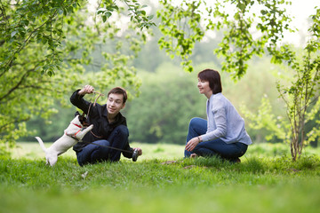 Fototapeta premium Portrait of happy mather with son and dog Jack Russell in summer park