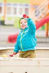 Adorable little boy is playing at the playground in a sandbox