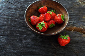Red fresh strawberries on black rustic wood background