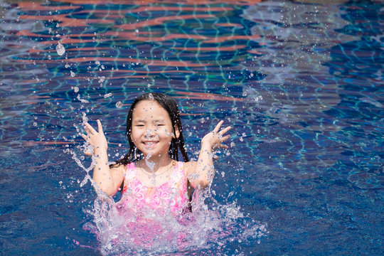 Asia kid girl at the pool and smiling happy