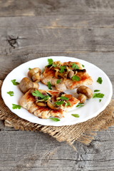 Fried Turkey steaks with cheese and mushrooms on a plate and on a burlap. Turkey meat garnish with green parsley and fried mushrooms. Old wooden background with free place for text