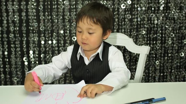 young boy draws with crayons