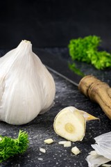 A garlic bulb and sliced garlic clove on granite board 