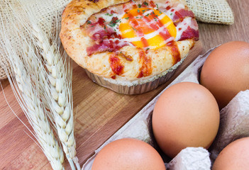 Baked sandwich with egg, cheese and ham. Hot breakfast. Bun with liquid egg, ham and melted cheese on natural wooden background.