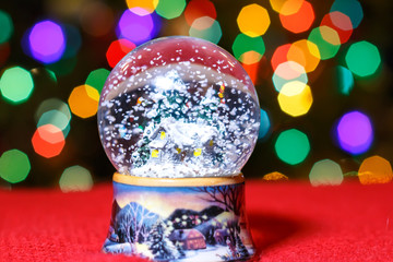 Christmas Snow Globe in front of Christmas tree lights closeup, blurred background