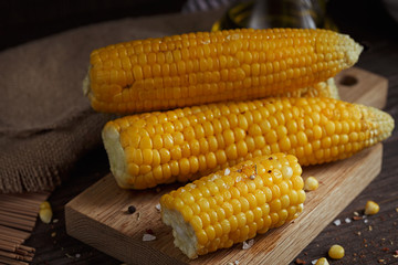 Golden corn cob with oil, herbs and salt on rustic wooden table