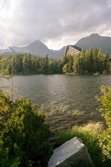 Obraz premium Vertical view of beautiful mountain landscape with hotel next to a lake. Strbske Pleso Town in High Tatras National Park, Slovakia.