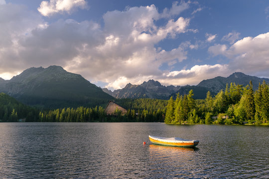 Peaceful mountain scene with mountain hotel next to a lake with boat. Scenic view of Strbske Pleso, High Tatras National Park, Slovakia.