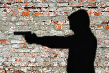 Silhouette von Mann mit Pistole auf Backsteinwand