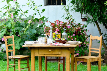 Fototapeta na wymiar Ländlich gedeckter Tisch mit Stühlen im Garten