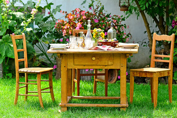 Ländlich gedeckter Tisch mit Stühlen im Garten