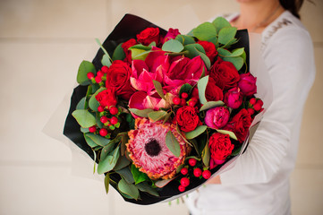 beautiful bouquet of different red flowers with black paper in hands