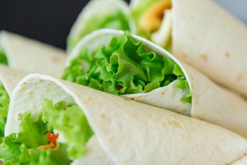 A man prepares to roll fast food.
chicken nuggets, lettuce, tomato, cheese, Mexican tortillas