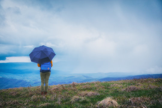 Girl with an umbrella on a mountain top.