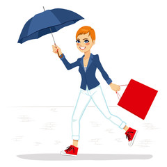 Beautiful woman in white jeans and blue jacket running with big blue umbrella and red shopping bag