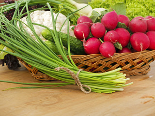 Spring vegetables in basket: radish, cucumber, chives and cauliflower