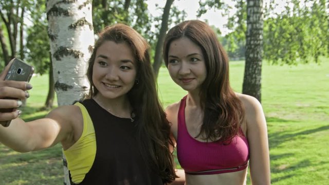 Women taking selfies after fitness exercises in the park