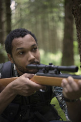 Interracial hunter in the forest aiming at prey