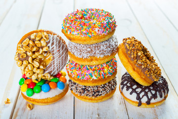 Collection of tasty donuts on white wooden board
