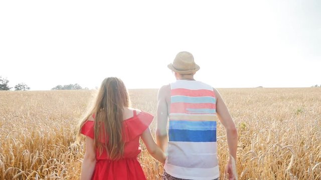 Happy young couple walking together through wheat field