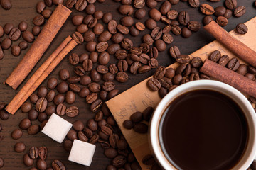 Cup of coffee, coffee beans, sugar cubes and cinnamon