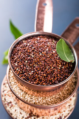 Stack of three copper measuring cups with mixed raw quinoa