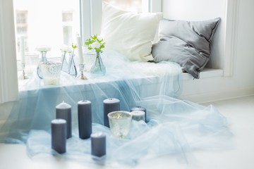 Decor of photostudio - gray candles, white and gray pillows, blue textile, artificials flowers