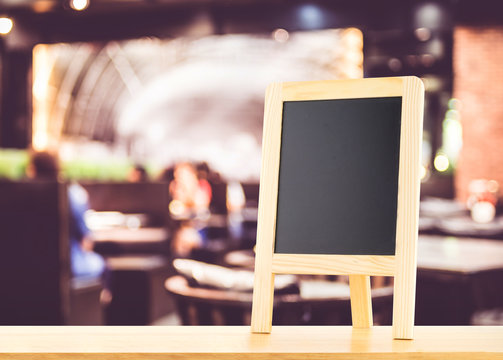 Blackboard with easel (menu board) on wooden table with blur bok