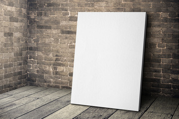 Blank white canvas frame leaning at grunge brick wall and wood f - obrazy, fototapety, plakaty