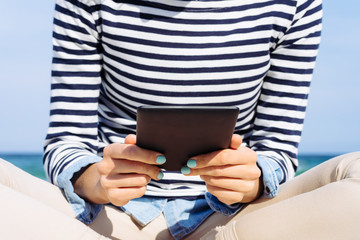 Close-up of a girl in a striped T-shirt with an e-book in hands