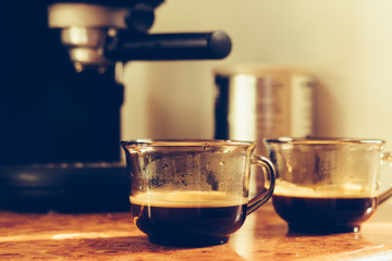 Two cups of coffee on the table near the coffee machine
