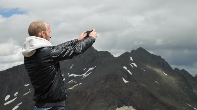 Tourist takes photos with smart phone on peak of rock