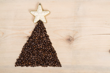 Christmas tree made from coffee beans on wooden background. Top