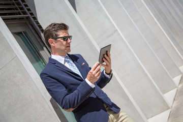 Business man in suit outside the office holding a tablet