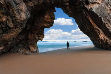 Lonely man at the rocky arch watching cloudy sky