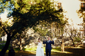 Fototapeta premium Bride and groom show their strong muscles posing on the green ba