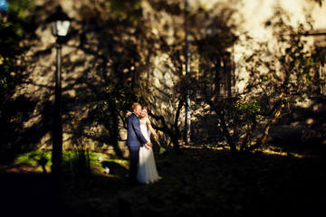 Bride reaches a hand with a bouquet out standing with a groom on