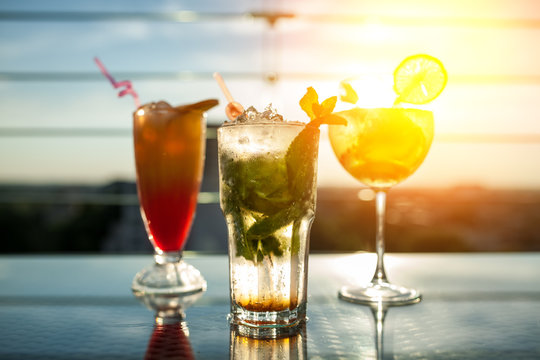 three exotic cocktails in rays of sun;