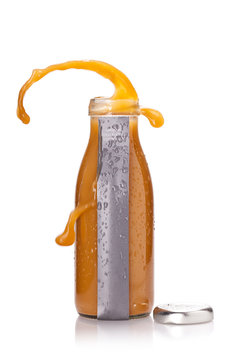 Bottle of juicy with orange liquid and popped cap