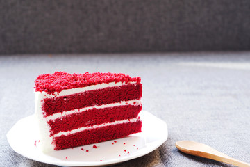 Close up of velvet cake on a white plate with dark background.