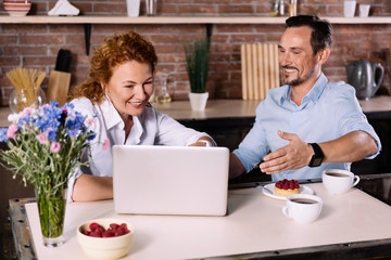 Couple looking at laptop while having breakfast