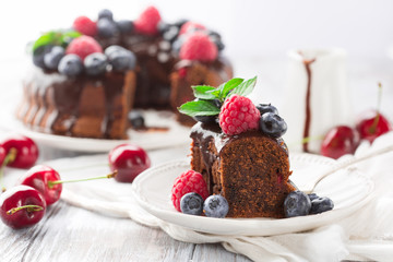 Chocolate cake with fresh summer berries - raspberry, blueberry and cherry on white wooden...