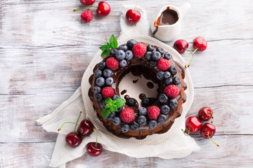 Homemade Chocolate cake with fresh summer berries - raspberry, blueberry and cherry on white table, top view