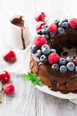 Chocolate cake with summer berries, white wooden table, selective focus