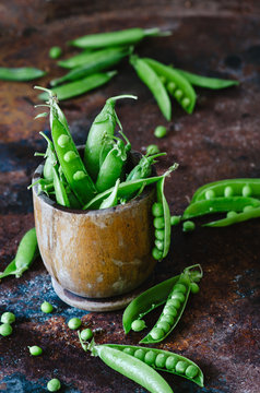 Bunch of mature pods of green peas on the old background in rustic style.