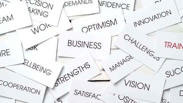 Business related concepts in a tag cloud on cards with one text in red: training. Success plan for a company. Dolly shot.