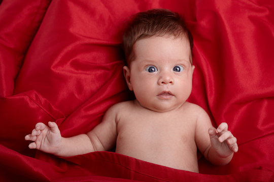 beautiful baby lying on red silk background