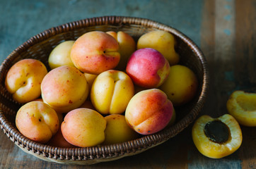 Fresh apricots in the basket on a wooden table in rustic style