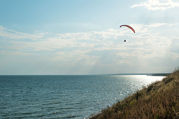 Paragliding in the sky. Man flying a paraglider on the sun.